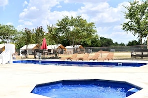 A swimming pool with lounge chairs and a barbecue grill.