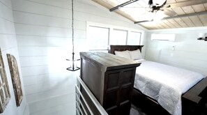 A bedroom with a bed, a wooden headboard, a ceiling fan, and a window.