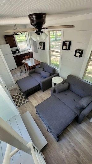 A compact living space with a kitchenette, a sofa, a dining table, and a ceiling fan.