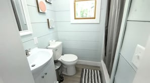Ein kleines Badezimmer mit Toilette, Waschbecken und einem kleinen Fenster.