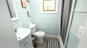 A compact bathroom with a toilet, sink, and a small window.