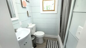 A compact bathroom with a toilet, sink, and a small window.
