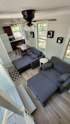 A compact living space with a kitchenette, a sofa, a dining table, and a ceiling fan.