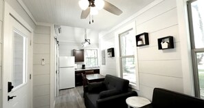 A compact kitchen with a refrigerator, a dining table, and a ceiling fan.