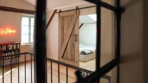 Une pièce comprenant un lit, une porte coulissante de style grange, une bibliothèque et un panneau lumineux au néon.