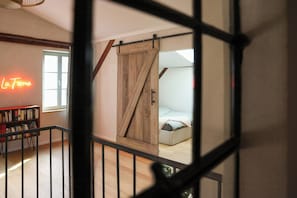 A room with a bed, a sliding barn door, a bookshelf, and a neon sign. - Idyllic hideaway in the countryside (Marienwerder)
