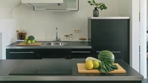 A modern kitchen with a black countertop, a built-in stove, a sink, and a black refrigerator. - Historic carriage house overlooking Havel (Werder (Havel))