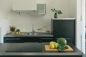 A modern kitchen with a black countertop, a built-in stove, a sink, and a dark cabinet.