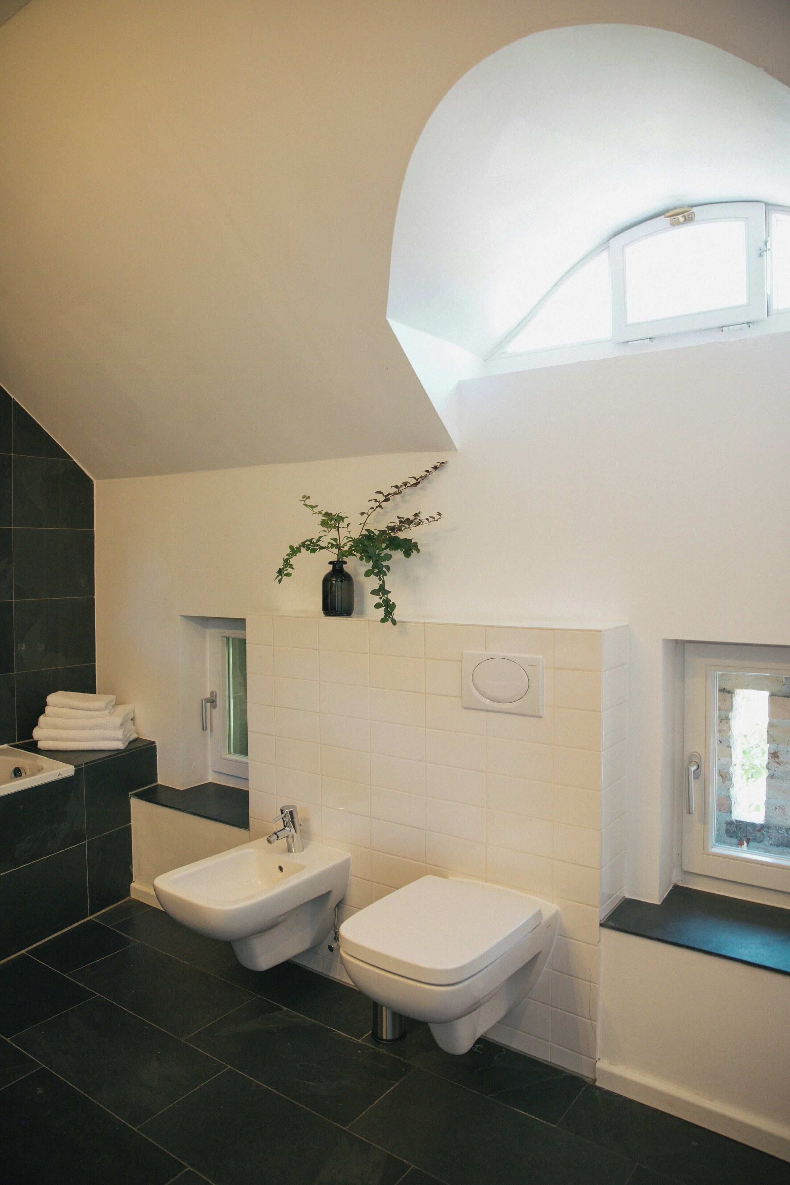 A modern bathroom with a bidet, toilet, and a window.