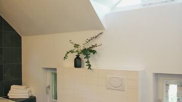 A modern bathroom with a bidet, toilet, and a window.