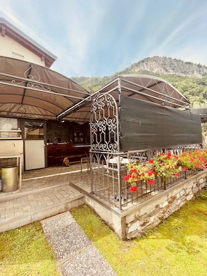 A covered outdoor seating area with a metal railing, potted plants, and a stone wall. - Mansarda Spadone Attic (Musso)