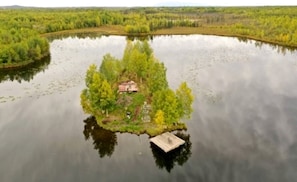 Una pequeña isla con un edificio rodeado de agua y vegetación.