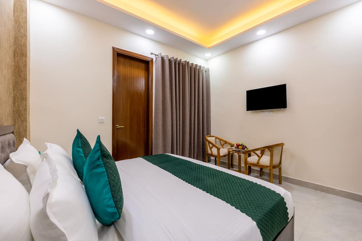 A hotel room with a bed, a desk, a chair, a television, and a door.