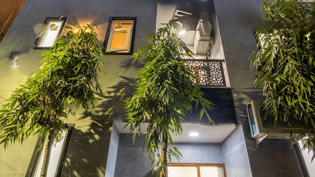 Un edificio moderno de varios pisos, con amplias ventanas y algo de vegetación al frente.