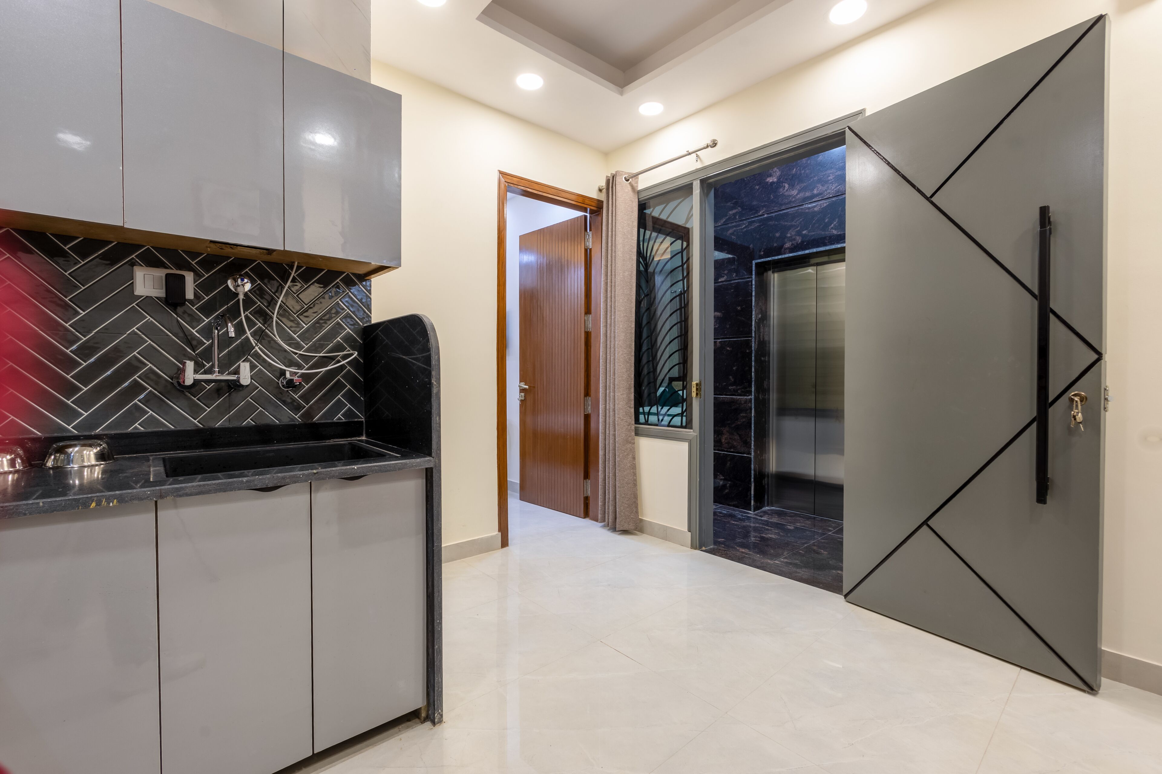 Una cucina moderna con rivestimento a spina di pesce, forno a incasso e una porta scorrevole che dà su un bagno con doccia in marmo.
