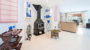 Een woonkamer met een open haard, een bank, een salontafel en een eethoek met een houten tafel en stoelen.