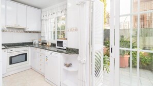 Een keuken met witte kastjes, een magnetron, een fornuis en een vaatwasser.
