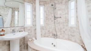 Een badkamer met een bad, wastafel en douche.