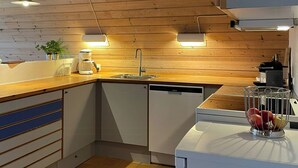 Eine moderne Küche mit Holzbalken, Pendelleuchten, einem Geschirrspüler und einer Obstschale.