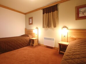 A room with two beds, a radiator, and two bedside lamps. - Appartment in Vaujany (Les Deux Alpes)