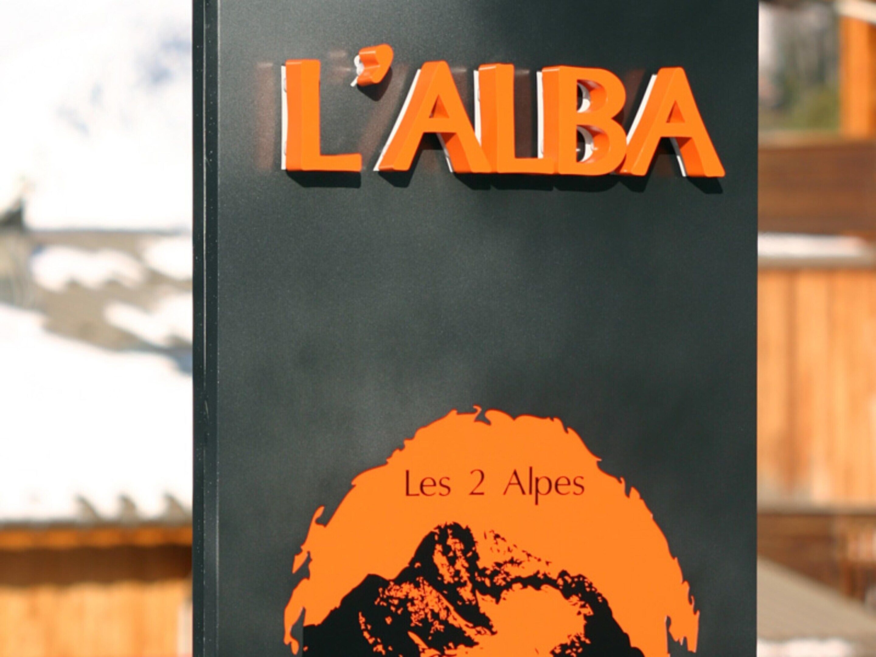 Un panneau indiquant « L’ALBA » et « Les 2 Alpes », signalant un lieu ou une destination.