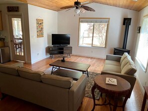 A living room with a sofa, a coffee table, a TV, a fireplace, and a ceiling fan.