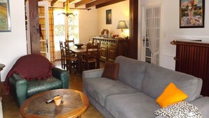 A living room with a sofa, a coffee table, a green armchair, and a fireplace. - Welcoming villa, pets allowed - 6 guests (Vielle-Saint-Girons)