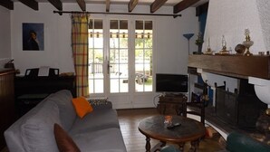A living room with a sofa, a table, a fireplace, and a window with curtains. - Welcoming villa, pets allowed - 6 guests (Vielle-Saint-Girons)