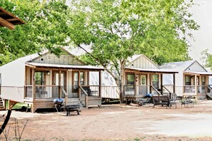 A row of mobile homes with wooden decks and steps, each with a grill and outdoor seating. - #7 Birdhouse Cabin in Seguin, TX (Seguin)