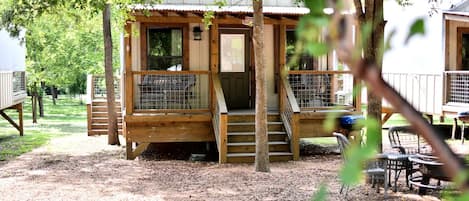 Une cabane en bois avec une véranda, un espace clôturé et du mobilier d’extérieur.