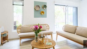 Ein Wohnzimmer mit einer Couch, einem Couchtisch mit Blumen und einem an der Wand befestigten Regal mit Dekoration.