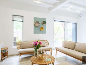 Ein Wohnzimmer mit einer Couch, einem Couchtisch mit Blumen und einem an der Wand befestigten Regal mit Dekoration.