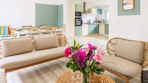 Ein modernes Wohnzimmer mit einer Couch, einem Esstisch und einer Küche im Hintergrund.