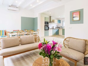 Ein modernes Wohnzimmer mit einer Couch, einem Esstisch und einer Küche im Hintergrund.