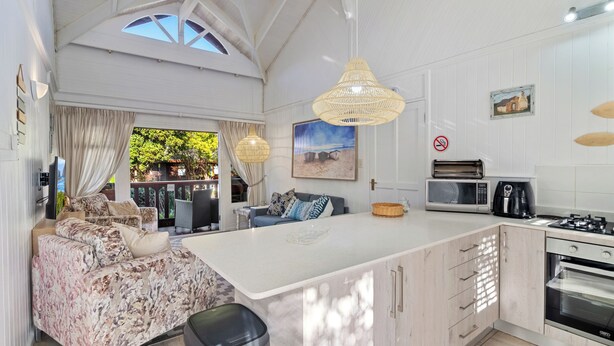 A modern kitchen with a large island, white cabinetry, a microwave, a coffee maker, and a view of the outdoors.