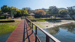 A wooden boardwalk over a body of water, surrounded by trees and buildings.