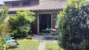 Una casa con un patio, un pequeño jardín y un camino que lleva a la entrada.