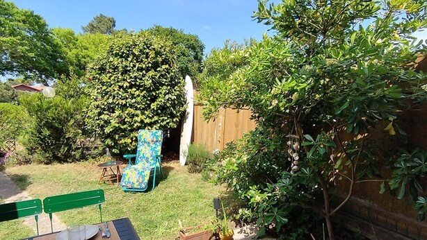 Un patio con una mesa lista para comer, una silla y una planta en maceta.