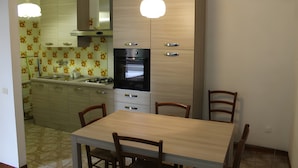 A kitchen with a dining table and chairs, a stove, oven, and cabinets. - Apartment 'Bilocale con Giardino Privato' with Exclusive Garden (Marina di Bibbona)