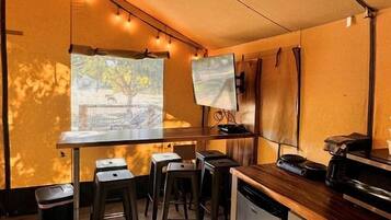 Cocina compacta con comedor, pantalla de proyector y un pequeño cubo de basura.