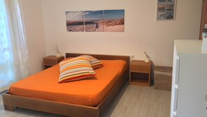 A bedroom with a wooden bed, two nightstands, a lamp, and a wall-mounted picture. - 'Prestige Apartment' with Shared Pool and Private Garden (Marina di Bibbona)