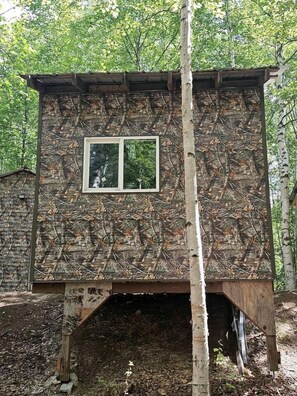A treehouse with a wooden exterior and a small window. - Relaxing Mini Cabin Hideaway with Campground Amenities, Play Area & Firepit in Houston, Alaska (Houston)