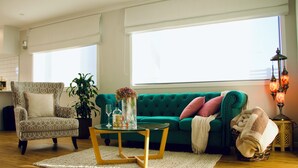 A living room with a green sofa, a patterned armchair, a glass coffee table, and a floor lamp. - Cozy Private Studio - Near Brewtown & Racecourse (Upper Hutt)