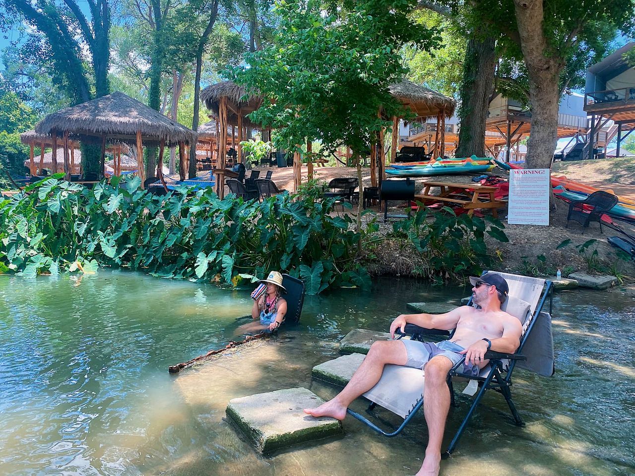 A pool area with lounge chairs and umbrellas, surrounded by tropical vegetation.