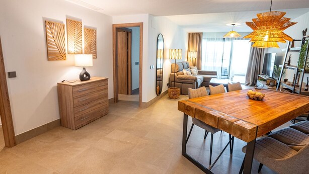 Een moderne eetruimte met een houten tafel en stoelen, een houten kast en een grote spiegel.