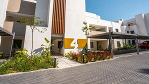 Een modern gebouw met een opvallend verticaal element, een overdekte parkeerplaats en een aangelegde entree.