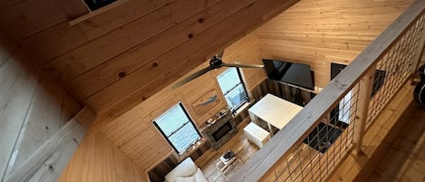 A wooden interior with a dining area, kitchen, and a view through a window.