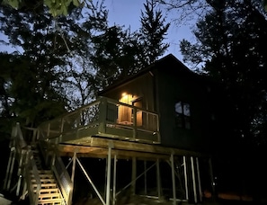 Ein Baumhaus mit einer Holzterrasse und einer Treppe, die hinaufführt.