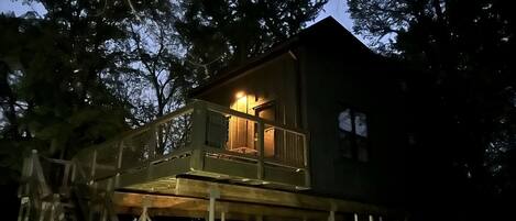 A treehouse with a wooden deck and a staircase leading up to it.