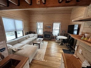 Ein gemütliches Blockhaus-Interieur mit Sofa, Couchtisch, Kamin und Holzwänden.